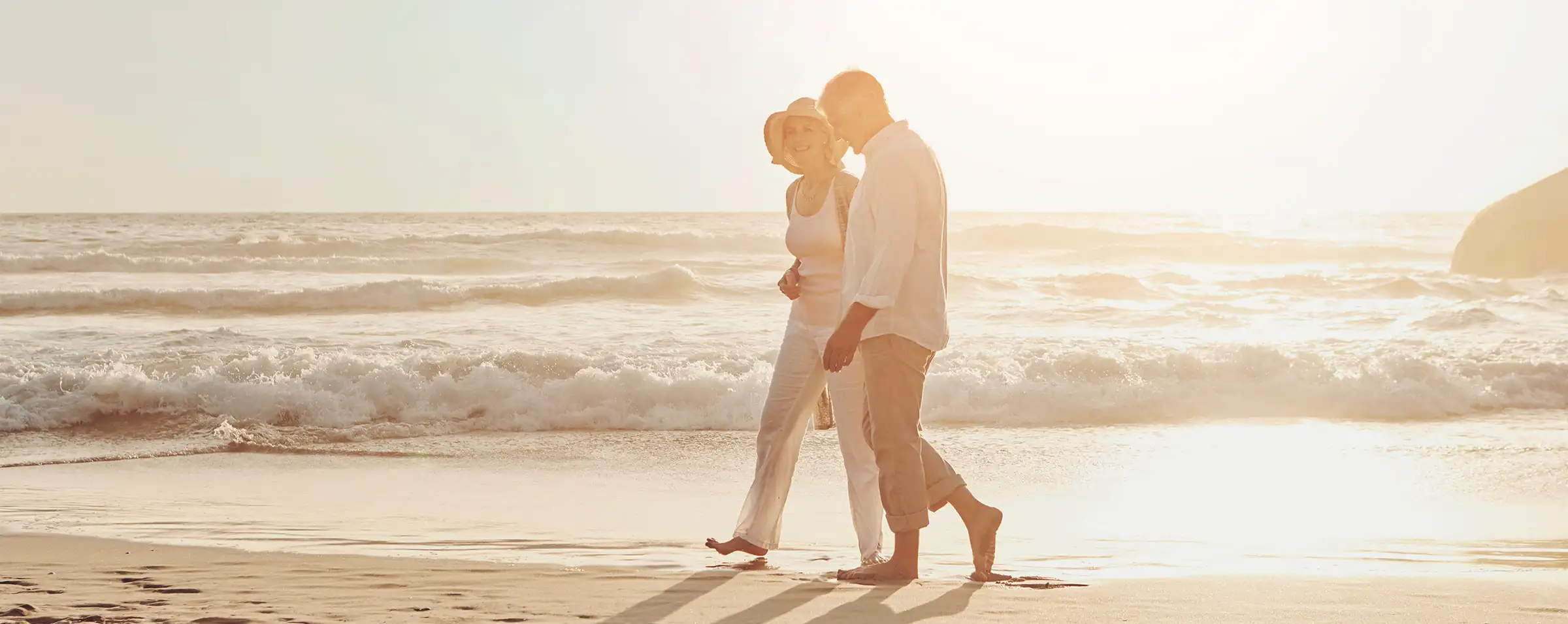 healthy senior couple after glaucoma treatment enjoying walk on the beach at sunset
