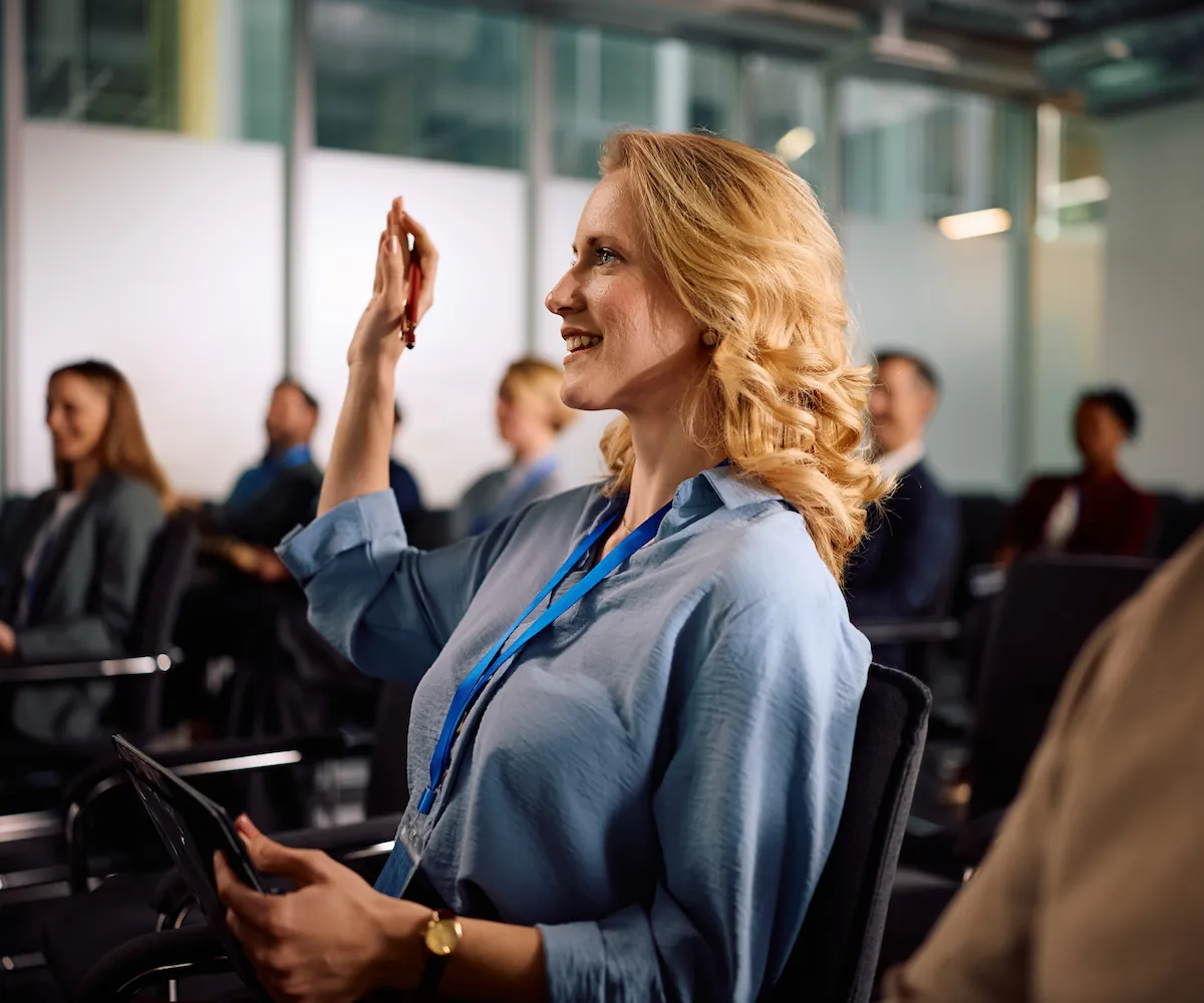 smiling medical professional in the audience raising hand at educational event for optometry